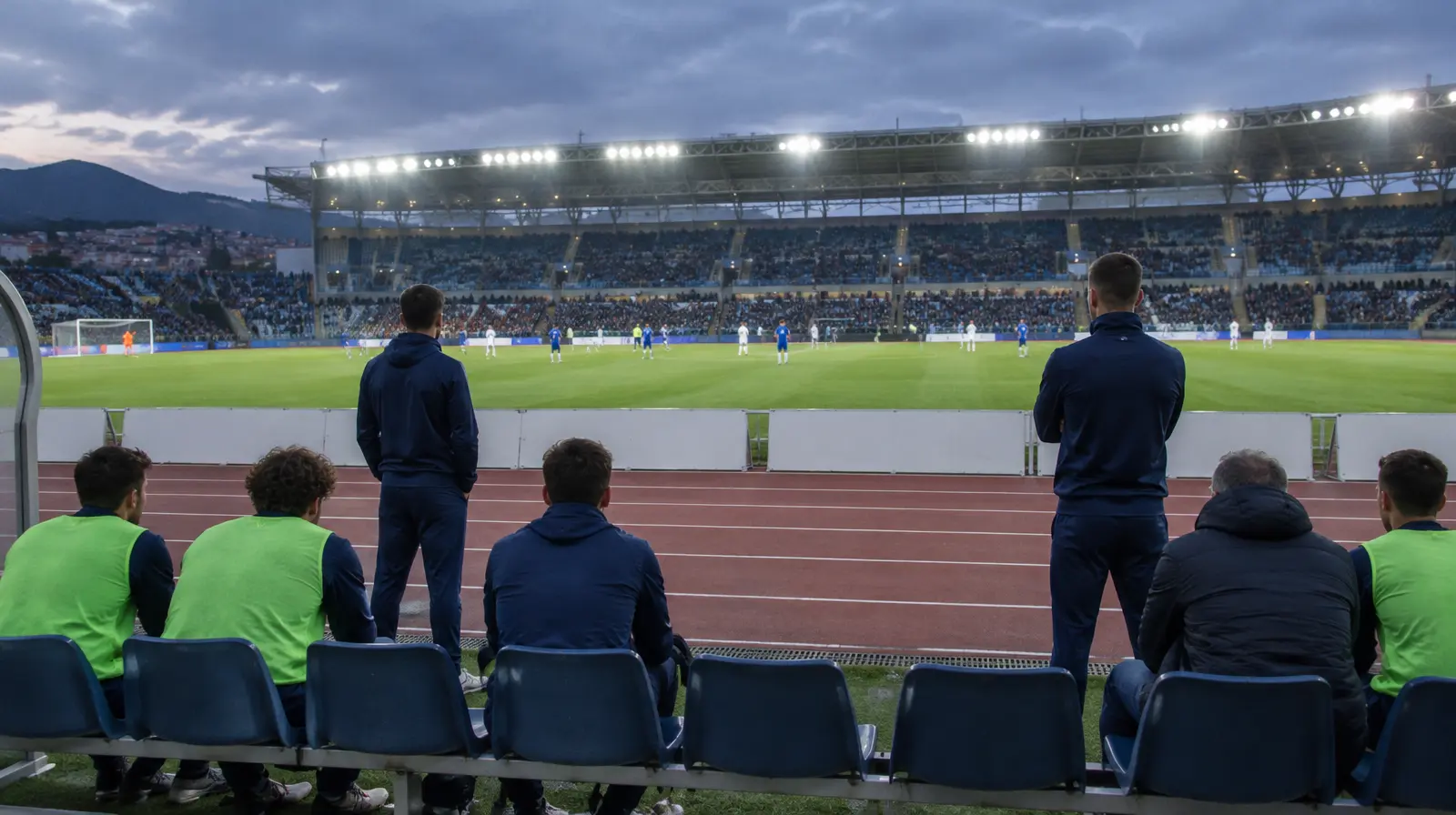 Avbytare och staben följer matchen från bänken i kvällsljus